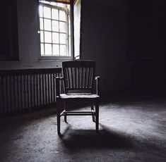 a chair sitting in an empty room next to a radiator with the light coming through