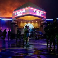 two people are kissing in front of a gas station at night with the lights on