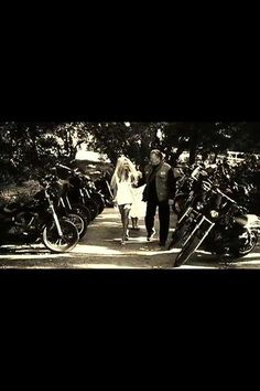 a man and woman walking down a road next to parked motorcycles