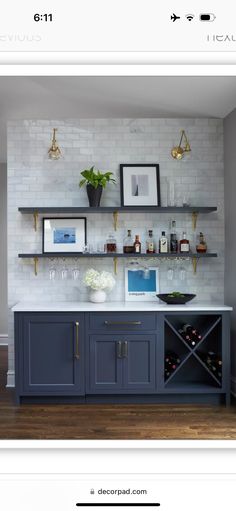 a kitchen with blue cabinets and shelves filled with wine glasses, bottles and vases