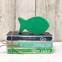 some books are stacked on top of each other with a green fish sitting atop them