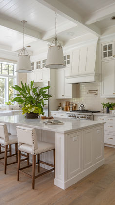 a large kitchen with white cabinets and an island in the middle is surrounded by chairs