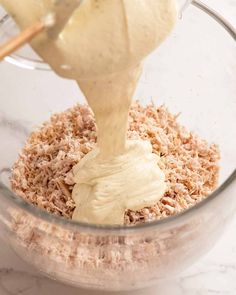 a person pouring batter into a bowl filled with oatmeal and other ingredients