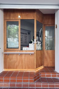 the front entrance to a coffee shop with wooden doors and glass windows on brick flooring