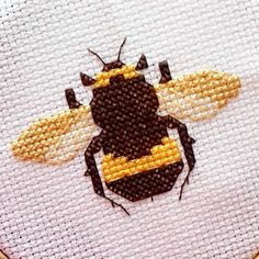 a close up of a cross stitch bee