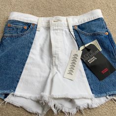 a pair of white and blue jean shorts with tags on the side, sitting on carpet