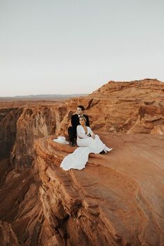 a couple sitting on top of a cliff next to each other