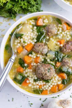 a white bowl filled with meatballs and veggies next to some parsley