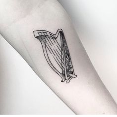 a black and white photo of a tattoo with a harp on it's arm