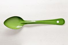 a green spoon sitting on top of a white table