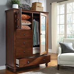 an armoire in a living room next to a chair