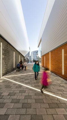 two people walking down a brick walkway next to a building