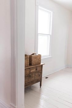 an empty room with white walls and wooden furniture