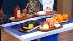 two trays filled with fruit on top of a blue counter next to oranges and apples