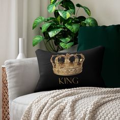 a white couch with a black pillow on top of it and a gold king crown