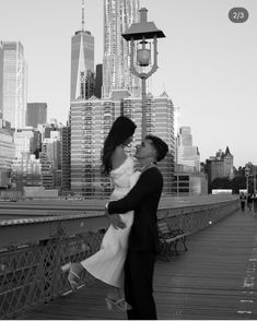 black and white photograph of a couple kissing on a bridge in front of the city skyline