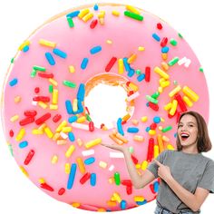 a woman holding a giant pink doughnut with sprinkles