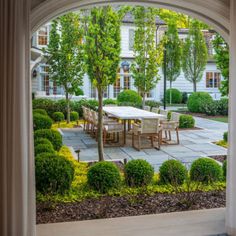 an open patio with table and chairs surrounded by bushes, trees, and shrubbery