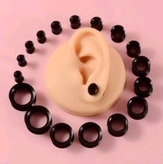 an assortment of black and white ear plugs on a pink background with space for text