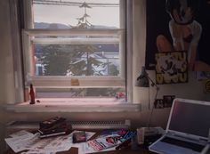 a laptop computer sitting on top of a wooden desk in front of a windowsill