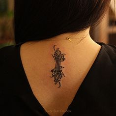 a woman with a tattoo on her upper back neck is looking down at the ground