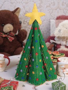 there is a small christmas tree on the table with other decorations and teddy bears around it