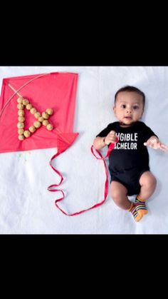 a baby laying on the ground next to a kite