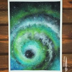 a painting of a green and blue spiral in the middle of wood planks with paintbrushes on it