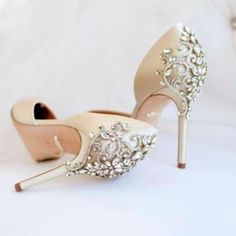 a pair of high heeled shoes with pearls and crystals on the heels are sitting on a white surface