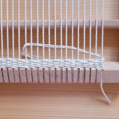 a close up of a weaving machine on a wooden table with white yarn in it