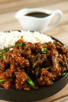 a close up of a plate of food with rice and sauce on the table next to a cup of coffee