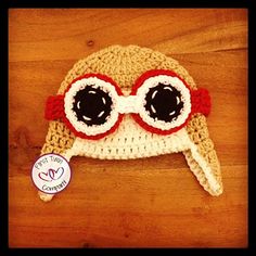 a crocheted hat with eye glasses on top of a wooden table next to a sticker