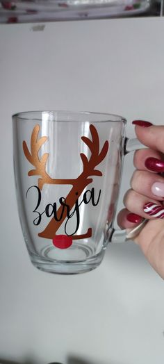 a woman holding a glass cup with reindeer decals on it and the words safffa written in black ink