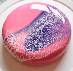 a pink and purple cake sitting on top of a white plate covered in icing