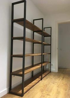 an empty room with wooden floors and shelving unit on the wall in front of it