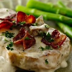 a green plate topped with meat covered in gravy and asparagus