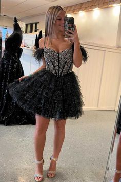 This homecoming dress, with its cold shoulder design accented by delicate feathers, is perfect for a night of dancing. The beaded top adds a touch of glamour while the tiered a-line skirt provides a flattering silhouette. Turn heads and feel confident in this glittery black dress. ♡ SKU: FV12894 ♡ Fabric: Tulle ♡ Silhouette: A-Line ♡ Back Style: Zipper ♡ Embellishment: Ruffles, Feathers ♡ Length: Above Knee ♡ Fully lined & Built with bra ♡ Size: US 2-16. True to the size chart. Check our Size Ch Glittery Black Dress, Its Cold, Homecoming Dresses Black, Short Homecoming Dress, Note Box, Beaded Top, Ruffle Shorts, Shoulder Design, Homecoming Dress