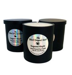 three black candles with labels on them sitting next to each other in front of a white background