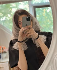 a woman taking a selfie in front of a mirror wearing a veil and gloves