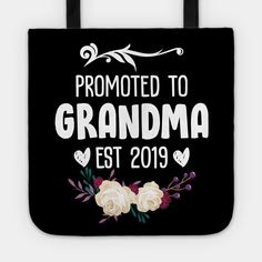 a black tote bag with white roses and the words, promote to grandma est 2019