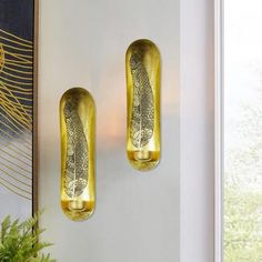 two gold vases sitting next to each other on a wall