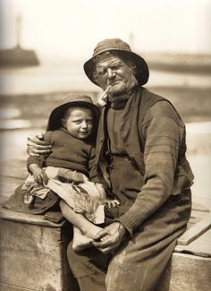 an old black and white photo of a man holding a child