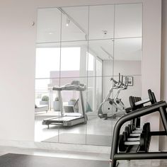 a gym with mirrors and exercise equipment in the foreground, on which there is a treadmill