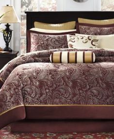 a bed with red and brown comforters in a room