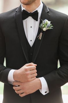 a man wearing a black tuxedo with a flower in his lapel