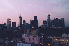 the city skyline is lit up at dusk with skyscrapers in the background and dark clouds