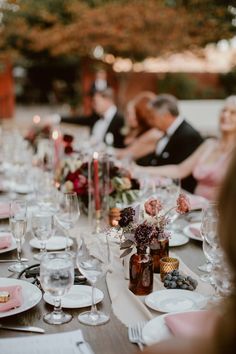 a group of people sitting at a table with plates and wine glasses on top of it