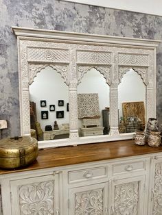 an ornate white dresser with mirrors and vases sitting on it's sideboard