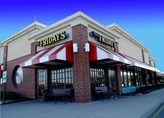 the friday's restaurant is located at the corner of an intersection in front of a building