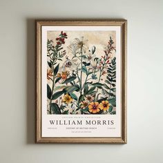 a framed poster hanging on the wall above a shelf with flowers and leaves in it